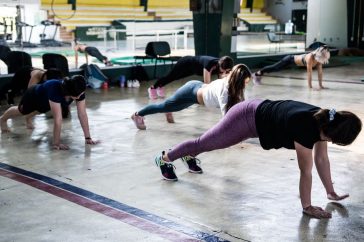 Group of women doing push-ups in a gym reflecting in a mirror.